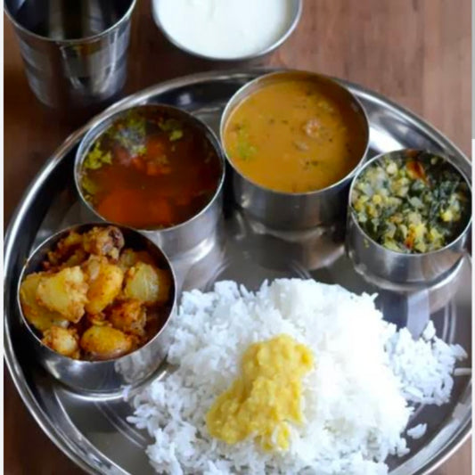 South Indian home cooked meals served on a traditional with rice, sambar, rasam, vegetable curry, and chutney